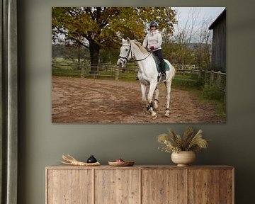 Training met het witte paard op een rijbak in de herfst