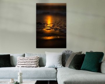 reflectie ondergaande zon op strand met dun laagje water