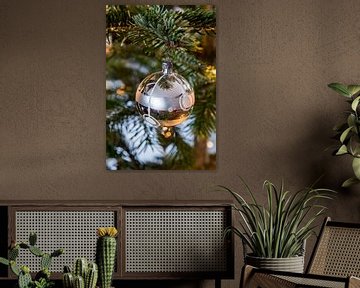 Zilverkleurige kerstbal en lichtjes in de kerstboom van Wim Stolwerk