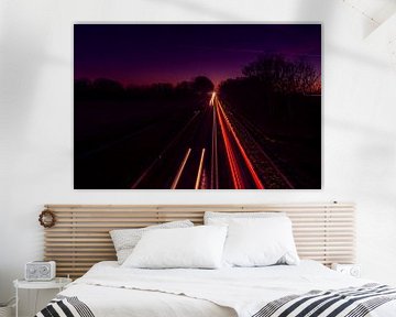 Beautiful glow in the sky with light trails on the road by Rob Baken