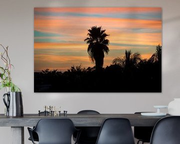 Perfecte palmboomzonsondergang met een kleurrijke oranje en blauwe lucht op de achtergrond van Michiel Ton