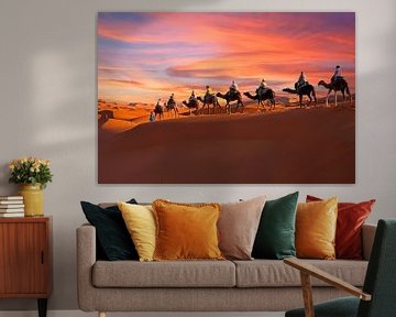 Une caravane de chameaux traverse le désert au coucher du soleil dans le désert du Sahara. sur Eye on You