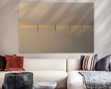 nebliger Sonnenaufgang über dem Wasser mit reflektierenden Pfählen und Pastellfarben von Kim Willems