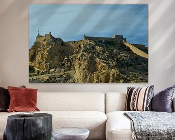 Het Castillo de Santa Bárbara in Alicante op een rotsachtige berg onder een strakblauwe hemel. van LuCreator