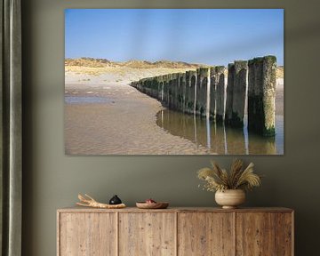 Holzpfähle in einer Reihe am Strand von Simone Janssen