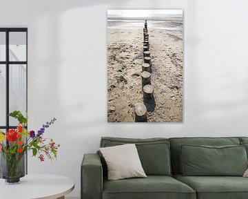 Rangée de poteaux en bois sur la plage, photographiée d'en haut sur Simone Janssen