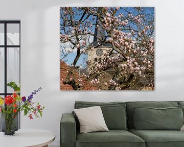 De kerk van Simpelveld met op de voorgrond een bloeiende Magnolia van John Kreukniet