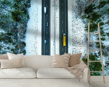 Snelweg door een besneeuwd boslandschap van bovenaf gezien