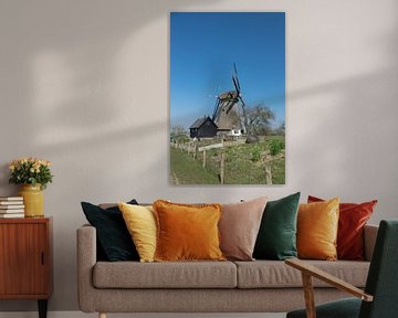 Wunderschöne holländische Windmühle auf einem Deich bei strahlend blauem Himmel
