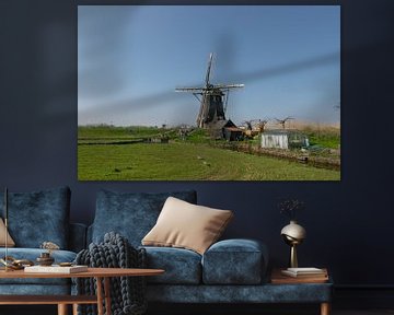 Mooie Hollandse windmolen aan een dijkje met een heldere blauwe lucht