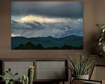 Zonneschijn door stormachtige wolken boven de bergen van Andreea Eva Herczegh