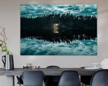 Leuchtende Hütte am spiegelnden See mit dramatischem Himmel von Joep van de Zandt