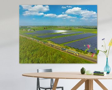 Trein van de Nederlandse Spoorwegen rijdt langs een veld met zonnepanelen